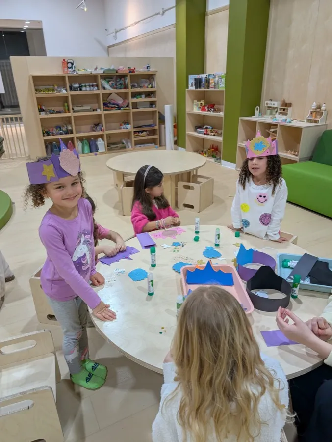 Littles in handmade paper crowns creating at a craft table inside Boogles Playhouse